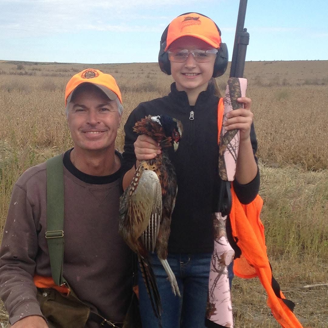 Marty Jackley with a young hunter holding her rooster pheasant